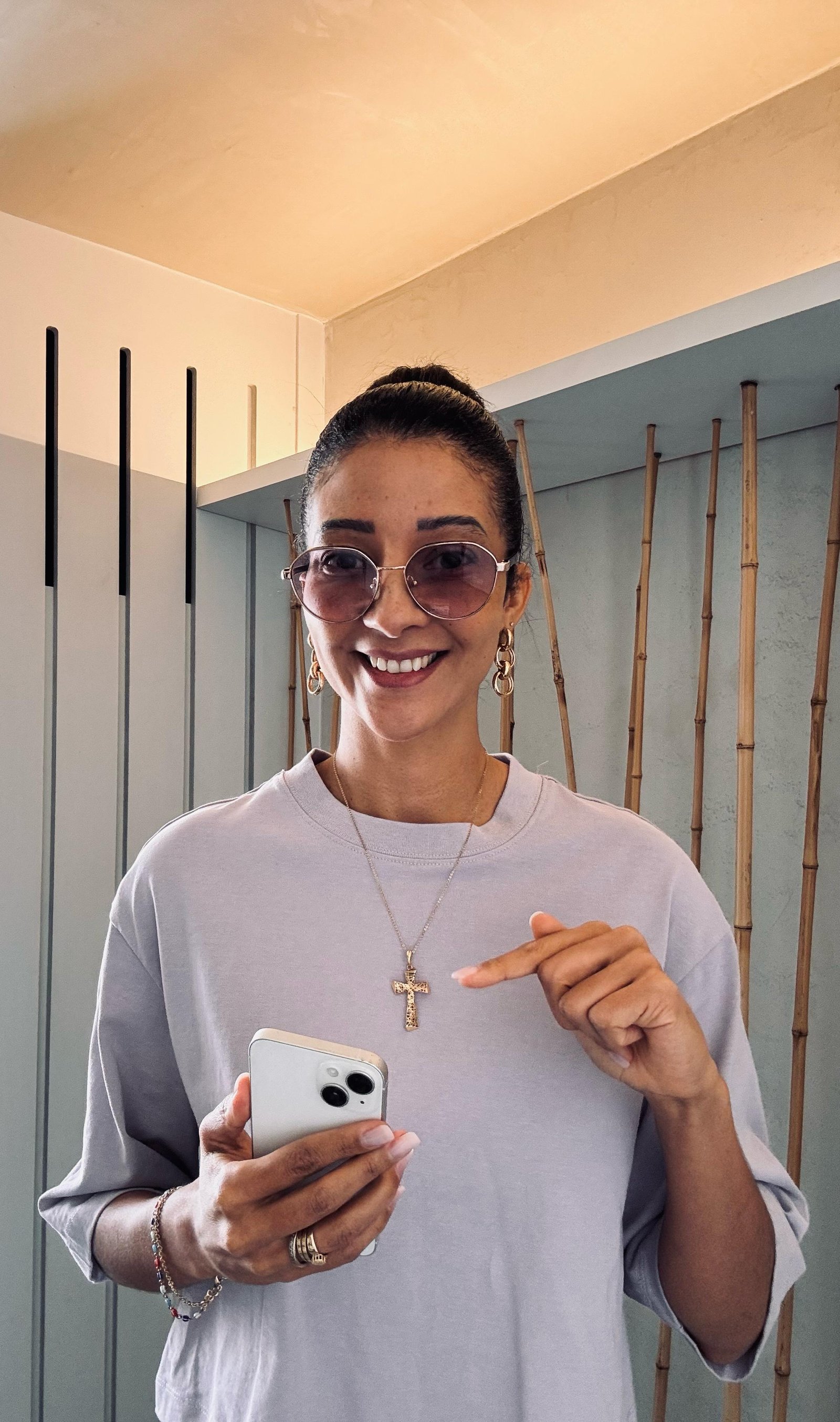 Lau sorrindo, segurando um celular e apontando para ele, convidando você a preencher o formulário